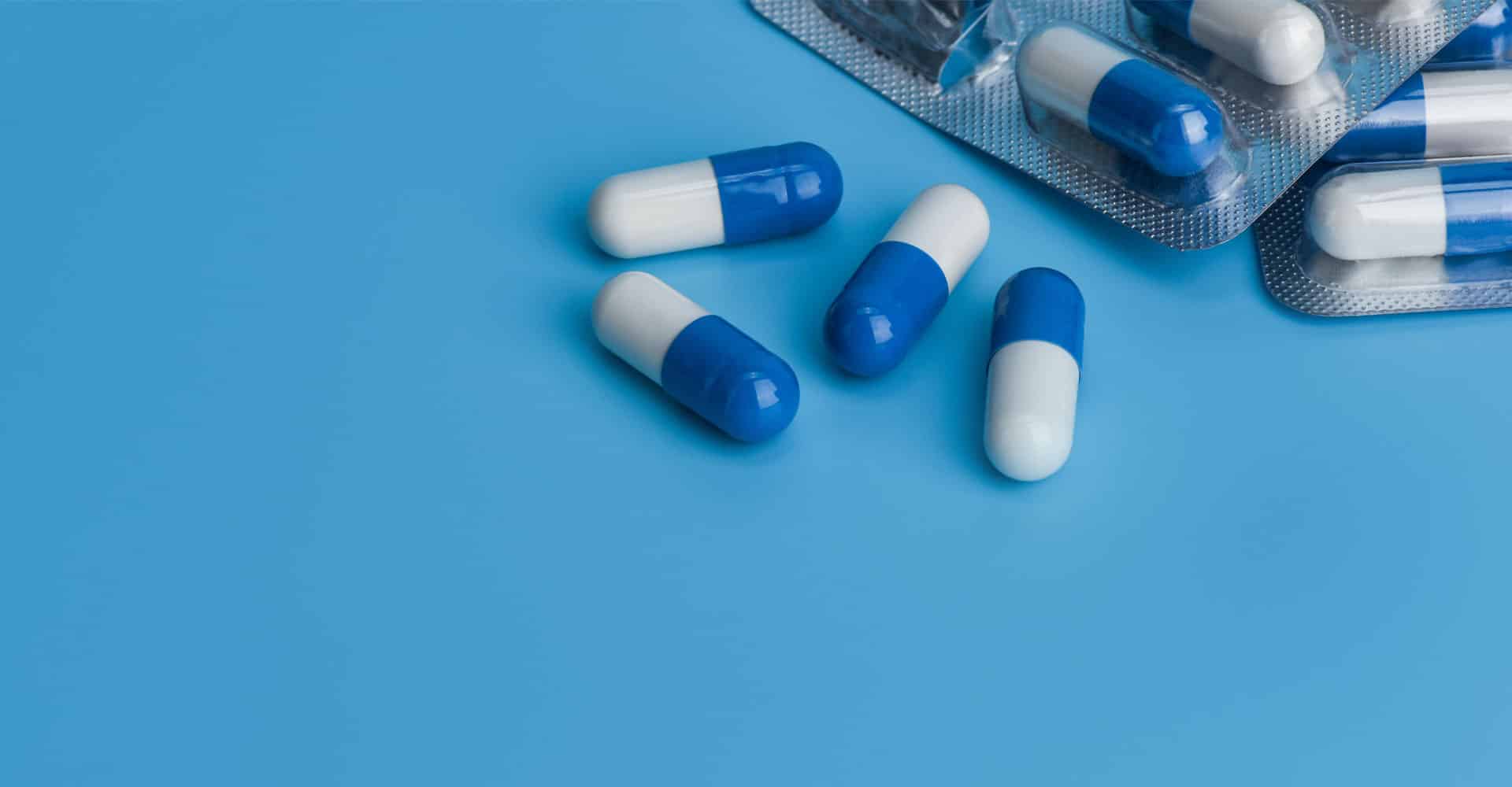 Is Pregabalin a Narcotic? Blue and white pill capsules on a blue surface.