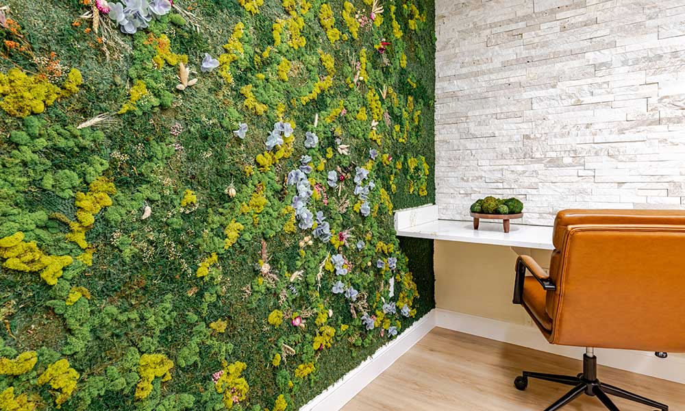 Office with green plant wall, brown chair, and white brick wall.