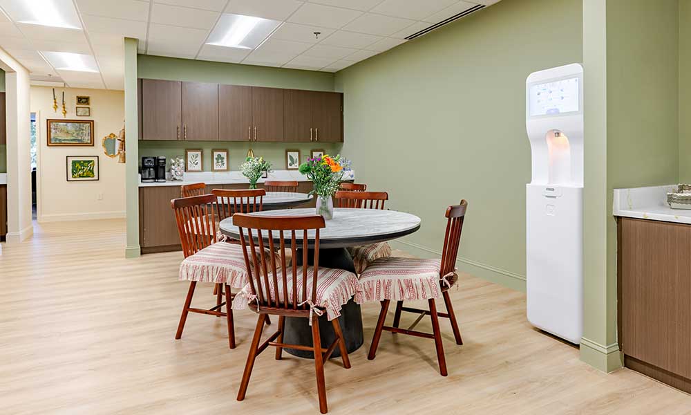 Dining area with wooden chairs, table with tablecloth, and green walls.