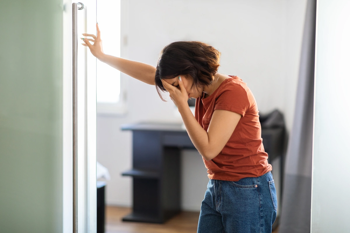 Effects of Lean Drink on the body: Person in orange shirt resting hand on forehead.