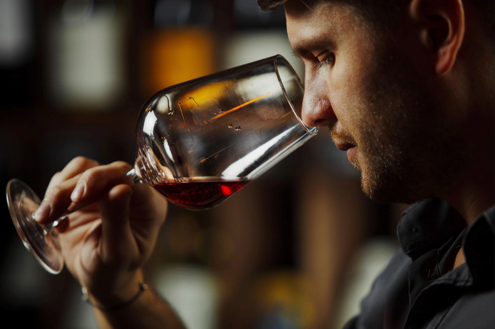 Person smelling red wine in a glass carefully.